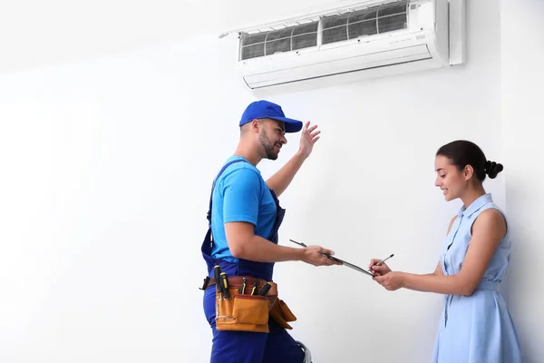 Técnico profissional falando com a mulher sobre ar condicionado dentro de casa — Fotografia de Stock