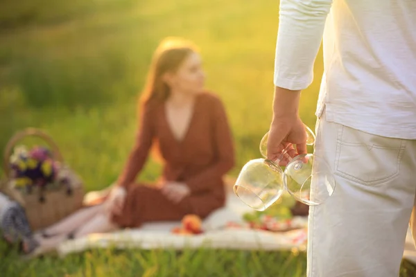 Şarap kadehli genç adam ve arka planda bulanık kadın, yakın plan. Piknik sezonu — Stok fotoğraf