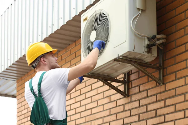 Professional technician repairing modern air conditioner outdoors — Stock Photo, Image