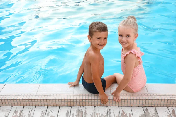 Lindos niños pequeños sentados en la piscina al aire libre — Foto de Stock