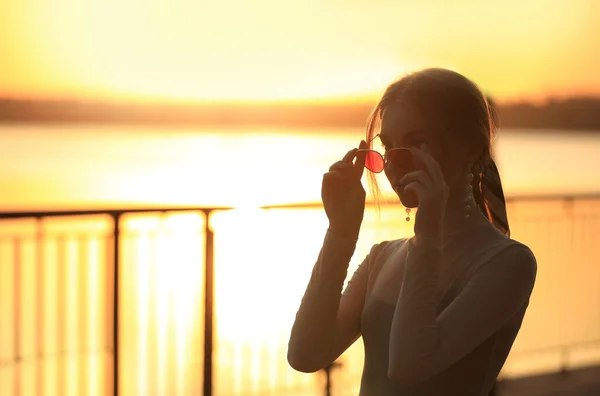 Silhueta de mulher jovem ao ar livre ao pôr do sol — Fotografia de Stock