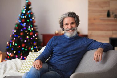 Mature man on sofa at home. Christmas eve