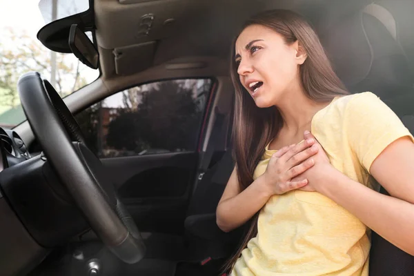 Mujer joven que sufre de un ataque al corazón en el coche —  Fotos de Stock