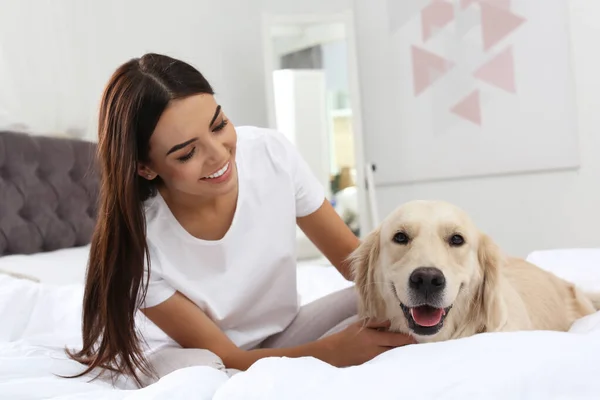 年轻女人和她的金毛猎犬躺在家里的床上 — 图库照片