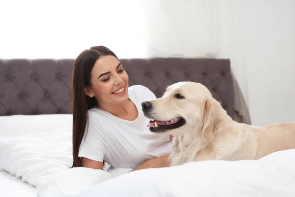 Jonge vrouw en haar Golden Retriever hond op bed thuis — Stockfoto