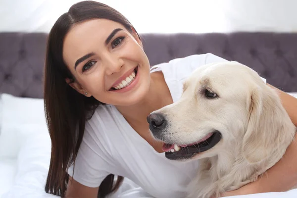 Jonge vrouw en haar Golden Retriever hond op bed thuis — Stockfoto