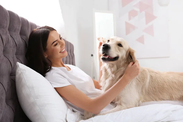 Jovem mulher e seu cão Golden Retriever na cama em casa — Fotografia de Stock