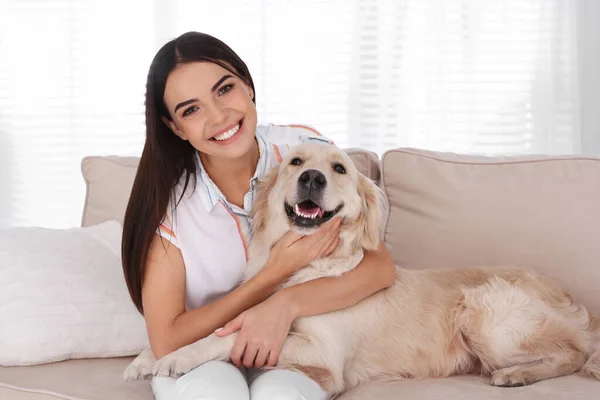 Mujer joven y su perro Golden Retriever en el sofá en la sala de estar —  Fotos de Stock