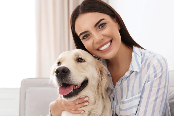 Jonge vrouw en haar Golden Retriever hond in de woonkamer — Stockfoto