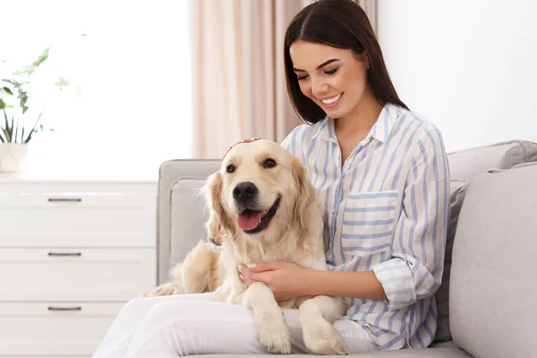 Jovem mulher e seu cão Golden Retriever na sala de estar — Fotografia de Stock