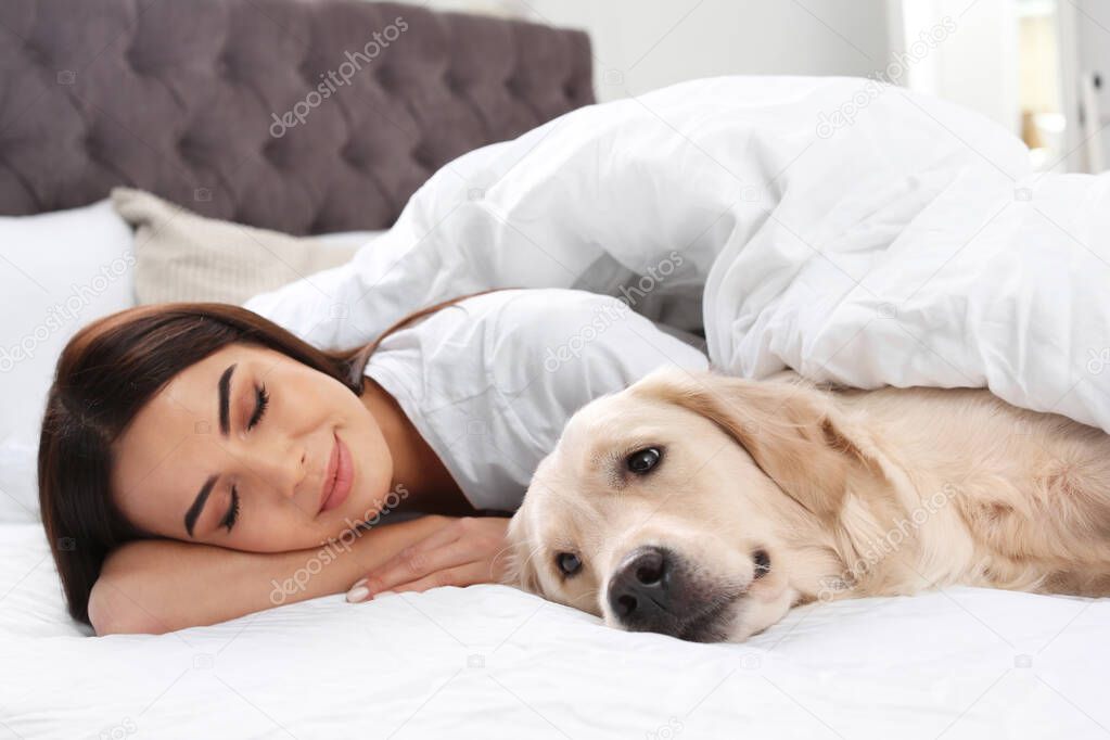 Young woman and her Golden Retriever dog on bed at home
