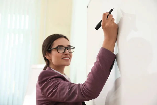 Vrouwelijke leraar schrijft op whiteboard in de klas — Stockfoto