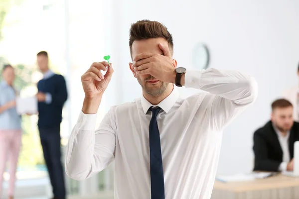 Jovem empresário jogando dardos com os olhos fechados — Fotografia de Stock