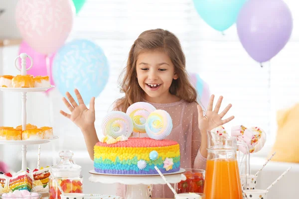 Happy girl at table with treats in room decorated for birthday party — Stock Photo, Image