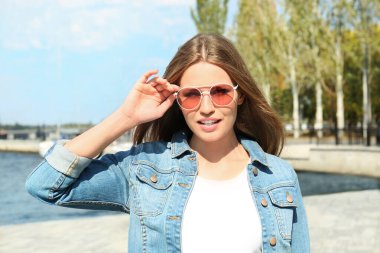 Nehir kenarında şık güneş gözlüğü takan genç bir kadın.