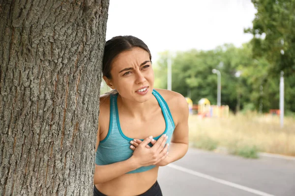 Young woman having heart attack while running outdoors