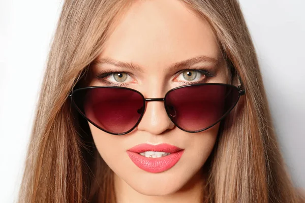 Młoda kobieta w stylowych okularach przeciwsłonecznych na jasnym tle — Zdjęcie stockowe