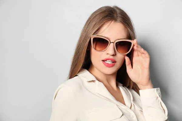 Young woman wearing stylish sunglasses on light background — Stock Photo, Image
