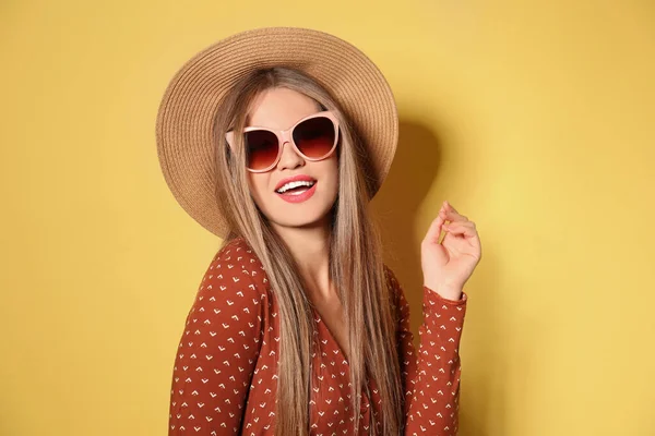 멋진 선글라스를 쓰고 노란 배경에 모자를 쓴 젊은 여자 — 스톡 사진