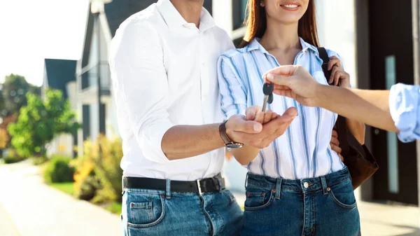 Makler übergibt Hausschlüssel an junges Paar im Freien, Nahaufnahme — Stockfoto