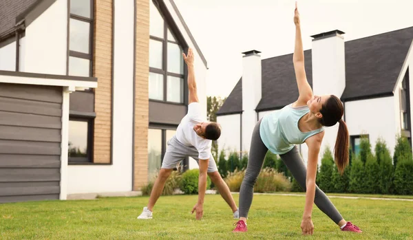 Pareja deportiva practicando yoga matutino en el patio trasero. Estilo de vida saludable — Foto de Stock