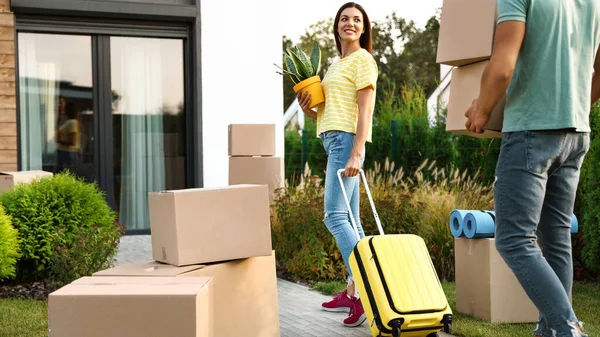 Couple walking to their new house with moving boxes and household stuff