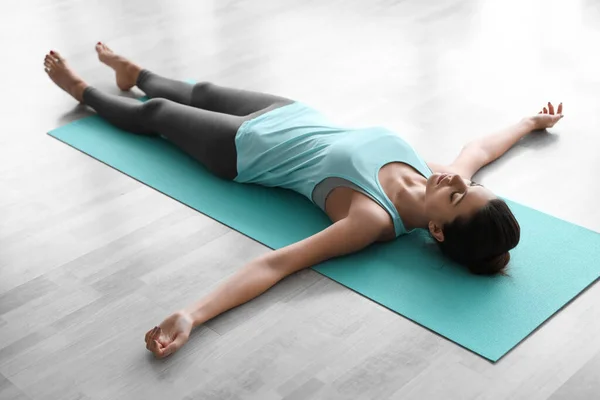 Jonge vrouw die asana in de yoga studio oefent. Savasana-houding — Stockfoto