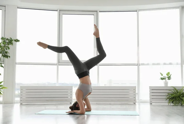 Giovane donna che pratica headstand con spacchi in studio di yoga — Foto Stock