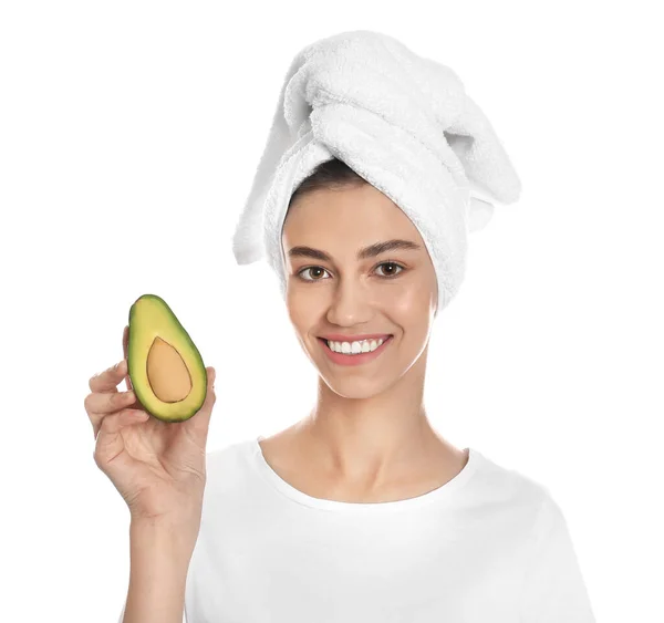 En lykkelig ung kvinne med håndkle som holder avokado på hvit bakgrunn. Organisk ansiktsmaske – stockfoto