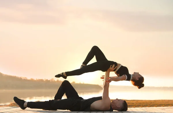 Vackra unga par tränar dans flyttar nära floden vid solnedgången — Stockfoto