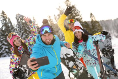 Bir grup arkadaş karlı tepede selfie çekiyorlar. Kış tatili