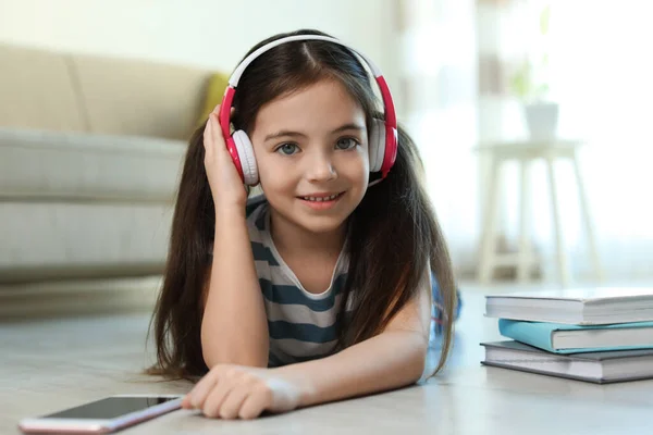 Schattig Klein Meisje Met Hoofdtelefoon Smartphone Luisteren Naar Audioboek Thuis — Stockfoto