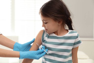 Modern klinikte küçük bir çocuğu aşılayan doktor.