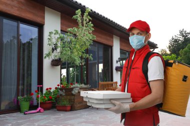 Koruyucu maskeli ve eldivenli bir kurye eve yakın bir yerde. Coronavirus karantinası sırasında teslimat servisi
