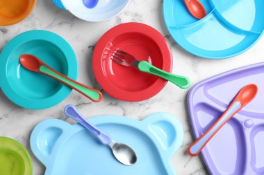 Beyaz mermer sehpanın üzerine renkli plastik bulaşık takımı. Bebek maması servisi.
