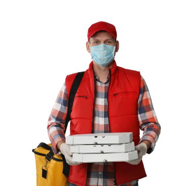 Koruyucu maskeli bir kurye ve arka planda pizza kutuları tutan eldivenler. Coronavirus karantinası sırasında yiyecek teslimatı