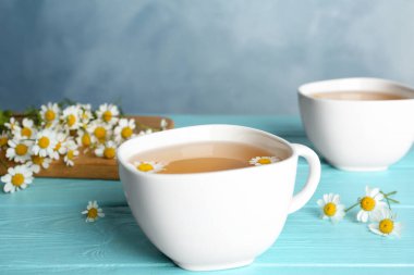 Açık mavi ahşap masada fincanda taze papatya çayı