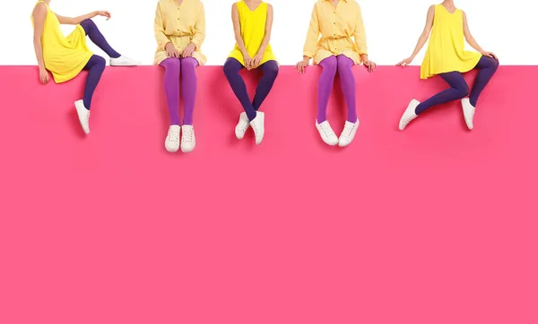 異なる明るいタイツとスタイリッシュな靴を身に着けている女性は 色の背景に座って クローズアップ — ストック写真