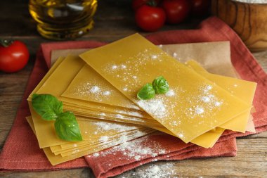 Ahşap masanın üzerinde pişmemiş lazanya çarşafları olan kompozisyon