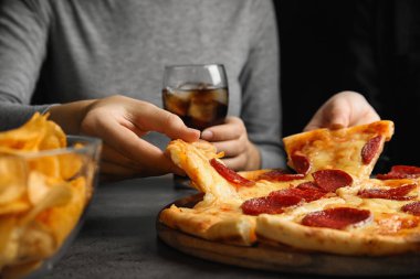 Gri masada lezzetli biberli pizza yiyen kadınlar, yakın plan.