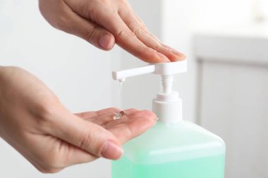 Kapalı mekanda antiseptik jel kullanan bir kadın.