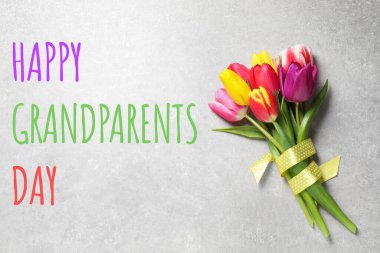 Güzel bahar laleleri ve cümleleri Mutlu büyük ebeveynler günü açık gri taş masa, üst manzara