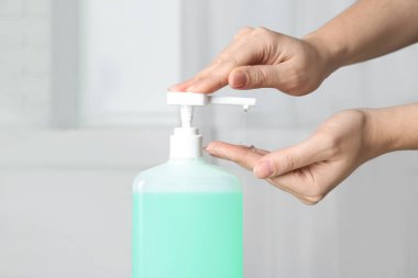 Kapalı mekanda antiseptik jel kullanan bir kadın.