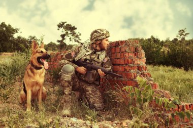 Atış poligonunda Alman çoban köpeği olan askeri üniformalı bir adam.