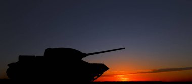 Gün batımında açık havada ordu tankının silueti. Askeri makineler.