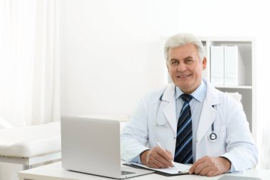 İş yerinde beyaz önlüklü kıdemli doktorun portresi.