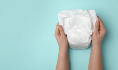 Turkuaz arka planda bebek bezi olan bir kadın, yakın plan. Metin için boşluk