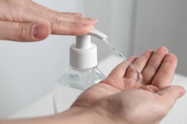 Kapalı mekanda antiseptik jel kullanan bir kadın.