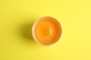 Sarı arka planda kırılmış çiğ tavuk yumurtası.