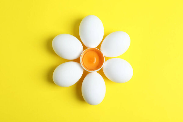 Fresh raw chicken eggs on yellow background, flat lay